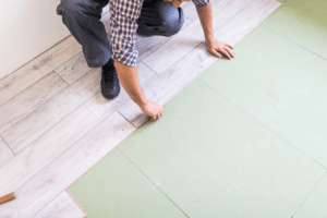 Man installing vinyl floors with green subfloor