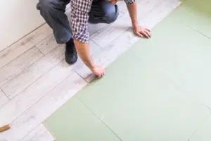 Man installing vinyl floors with green subfloor