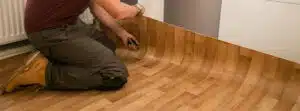 Man installing vinyl planks with utility knife in hand