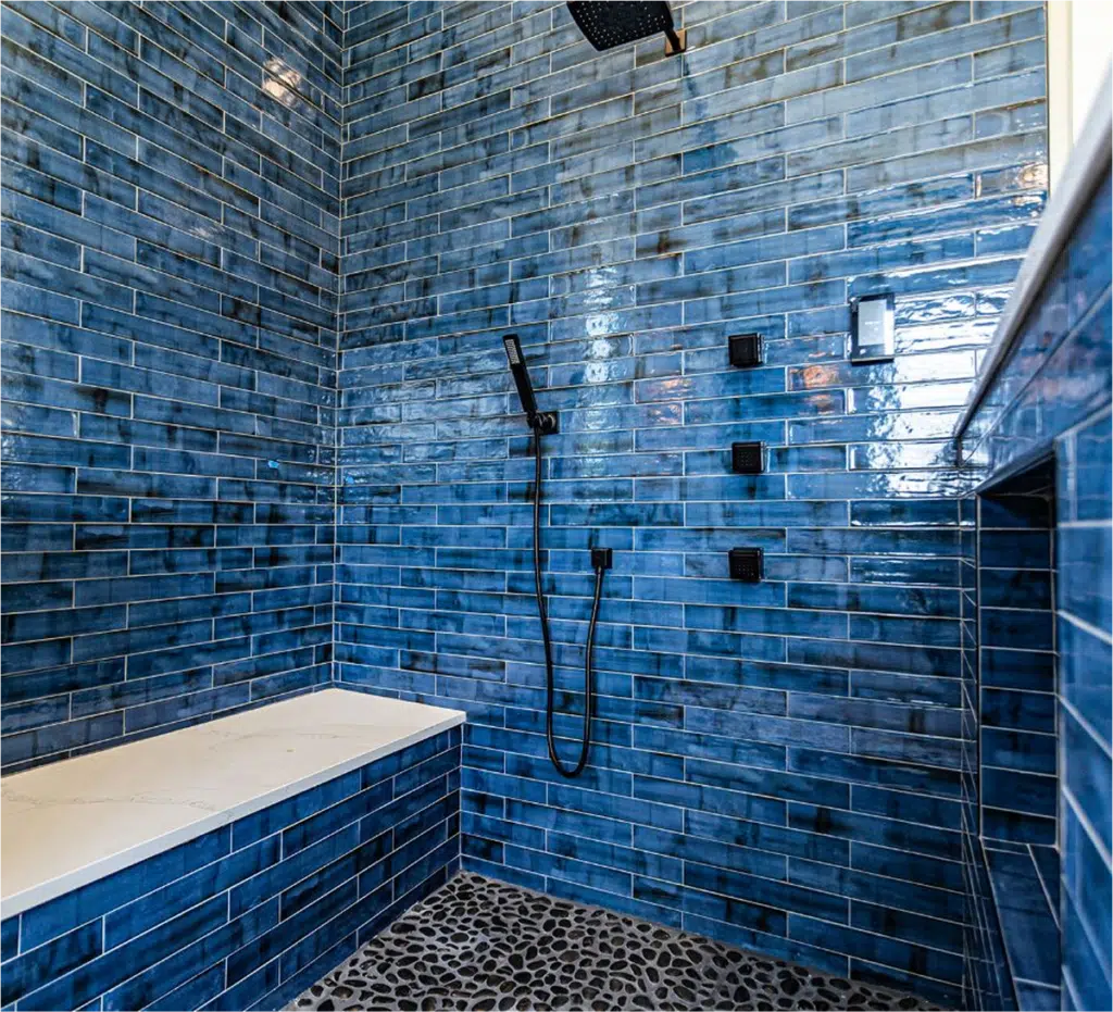 Luxurious blue-tiled shower with rainfall showerhead and pebble floor.