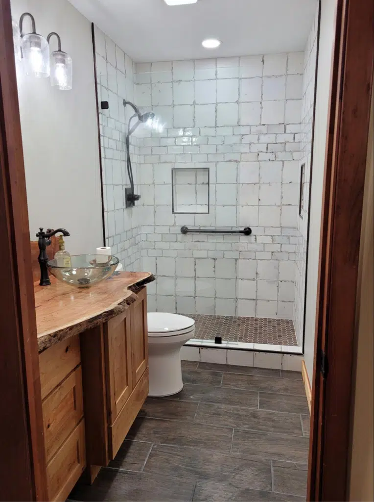 Rustic bathroom featuring a live-edge wood vanity, white subway tiles, and a walk-in shower.