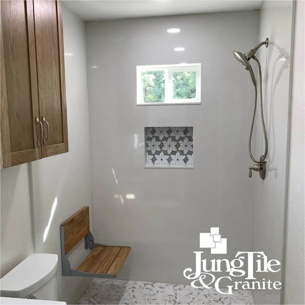 Minimalistic shower with white walls, wooden bench, and decorative tile niche.