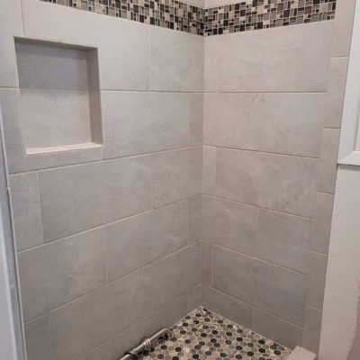 large white tiles on shower wall with small tiles on floor